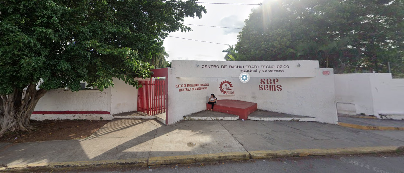 Fotografía en la que se muestra la fachada del plantel, conformada por una reja roja y alrededor muros de color blanco. Sobre el muro del lado derecho en letras rojas, está escrito el siguiente texto: CENTRO DE BACHILLERATO TECNOLÓGICO INDUSTRIAL Y DE SERVICIOS.